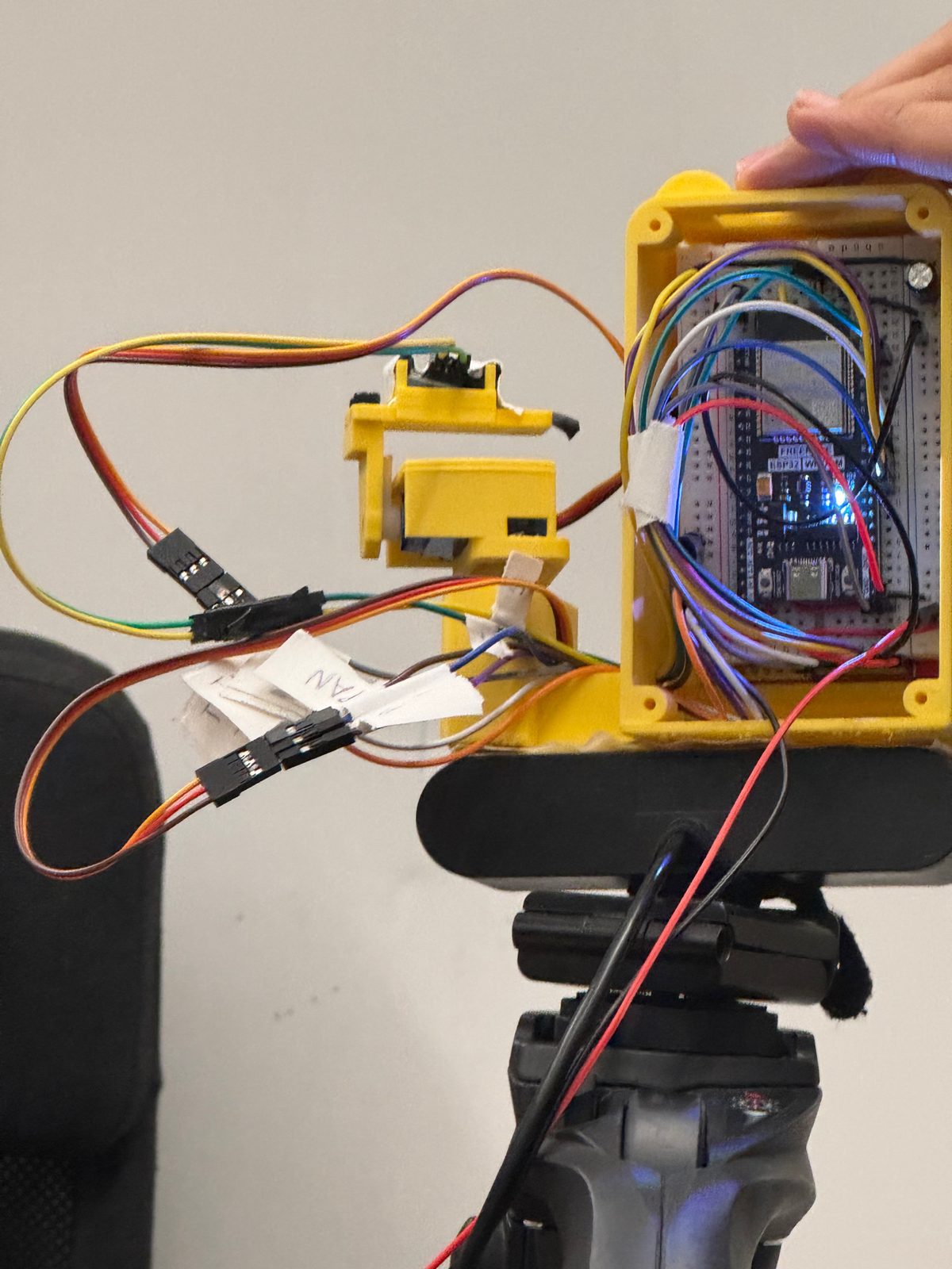 The back of the robot opened up: the ESP32 on a small breadboard inside the yellow case, with jumper wires running to the servos and the laser arm.